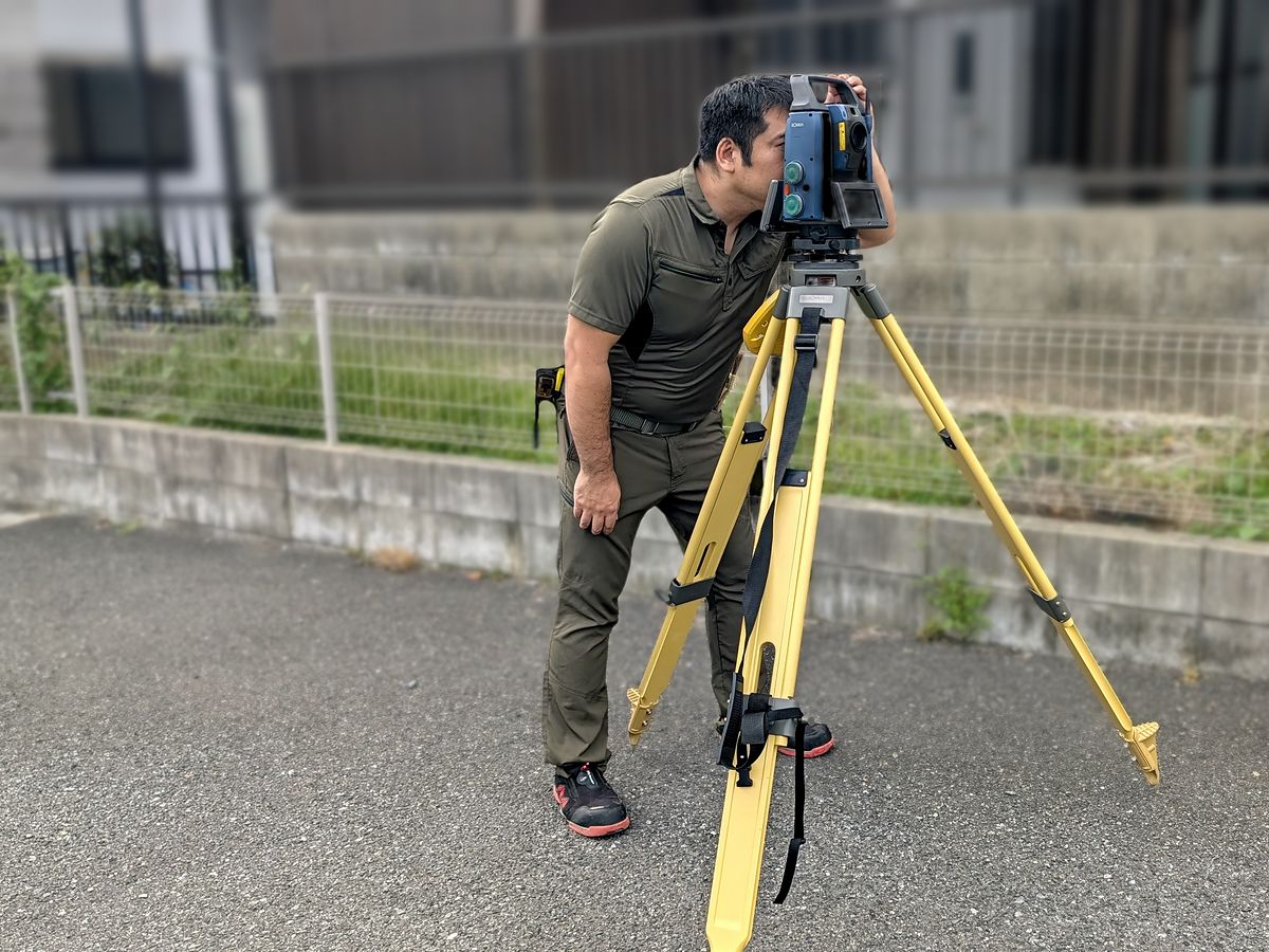 測量機をのぞいて位置を測る土地家屋調査士
